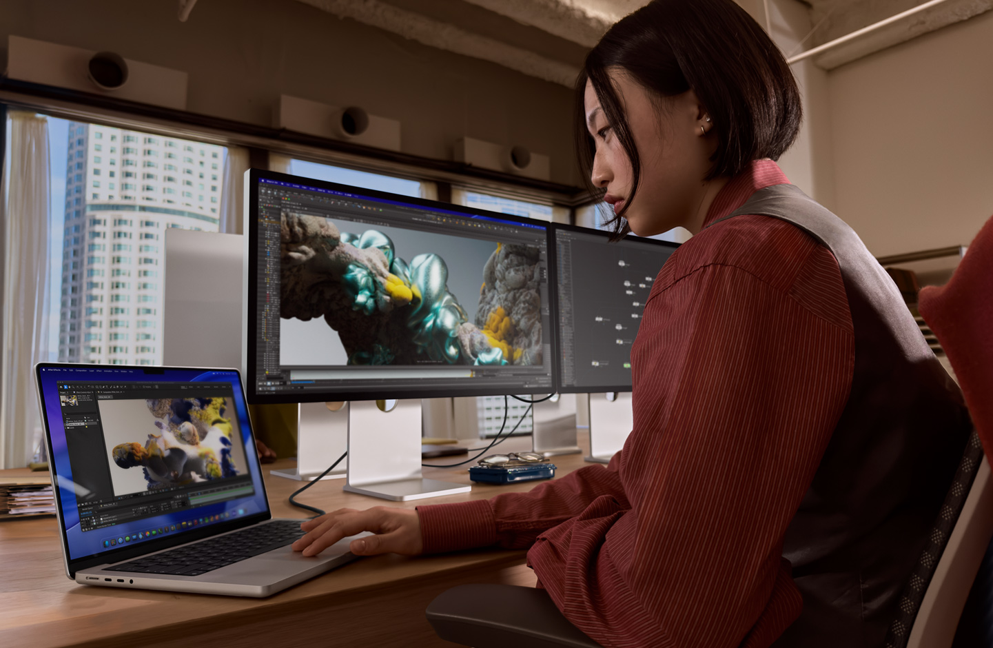 ?lověk v kancelá?i pracuje na MacBooku, ke kterému je p?es port Thunderbolt 5 p?ipojeny Studio Display XDR