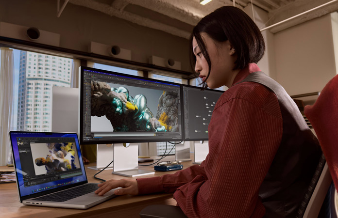 En person som arbetar i en kontorsmilj? med en MacBook Pro som ?r ansluten till Studio Display XDR