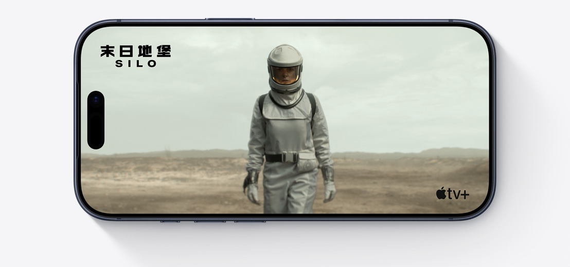 橫放的 iPhone，機(jī)身正面，螢?zāi)伙@示 Apple TV 劇集《末日地堡》(Silo) 的劇照，角色身穿太空衣