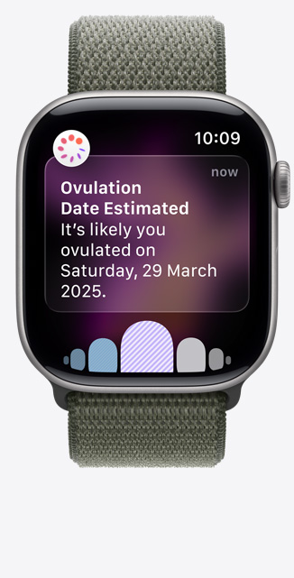 Apple?Watch Series?11，太空灰鋁金屬錶殼，展示透過健康?app 經(jīng)期追蹤收到的排卵日期推算通知、數(shù)碼錶冠，配搭森林色運(yùn)動(dòng)手環(huán)