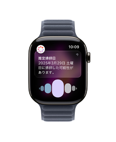 スレートチタニウムケースのApple Watch Series 11。ヘルスケアアプリの周期記録から推定される排卵日の通知が表示されている。Digital Crownが見えていて、ネイビーのマグネティックリンクバンドが取りつけられている