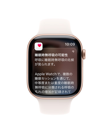 ローズゴールドアルミニウムケースのApple Watch Series 11。畫面に睡眠時(shí)無呼吸の通知が展開されている。右側(cè)面の外観、Digital Crown、ライトブラッシュのスポーツバンド