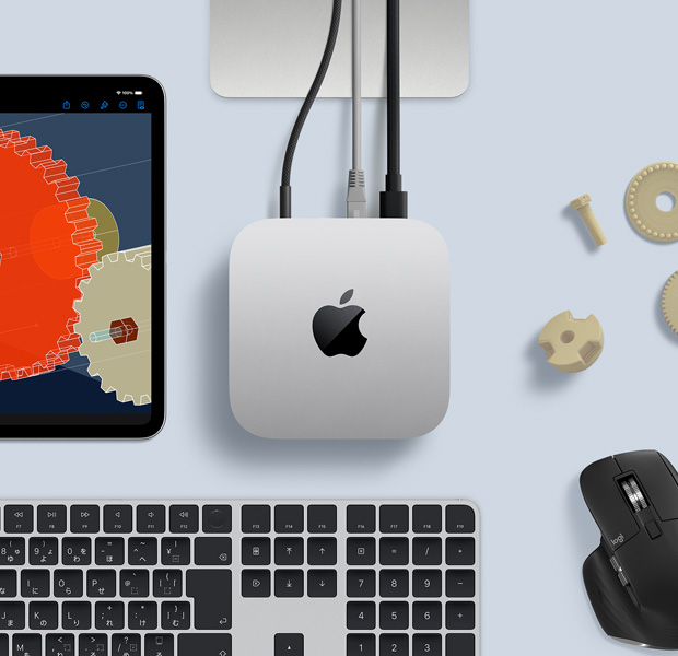 デスク上に置かれたシルバーのMac miniを上から見た図。ブラックとシルバーのワイヤレスキーボード、ブラックのワイヤレスマウス、iPadが一緒に配置されている