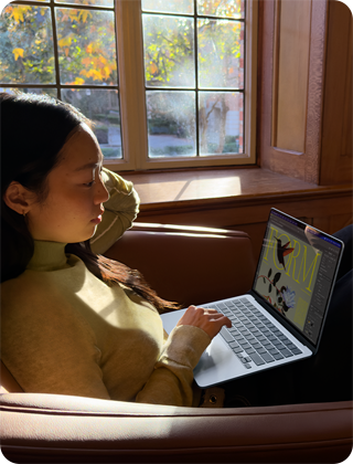 Cilvēks, kas sē? krēslā un strādā ar savu MacBook Air