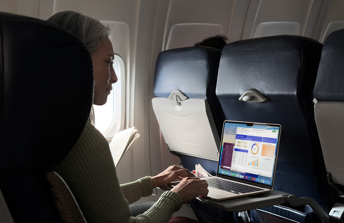 Osoba siedz?ca w samolocie i pracuj?ca na MacBooku Air