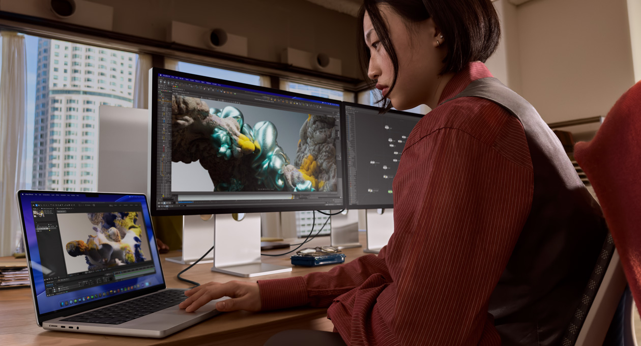 Людина в оф?с? працю? на ноутбуку MacBook, п?дключеному до мон?тора Studio Display XDR через порт Thunderbolt 5