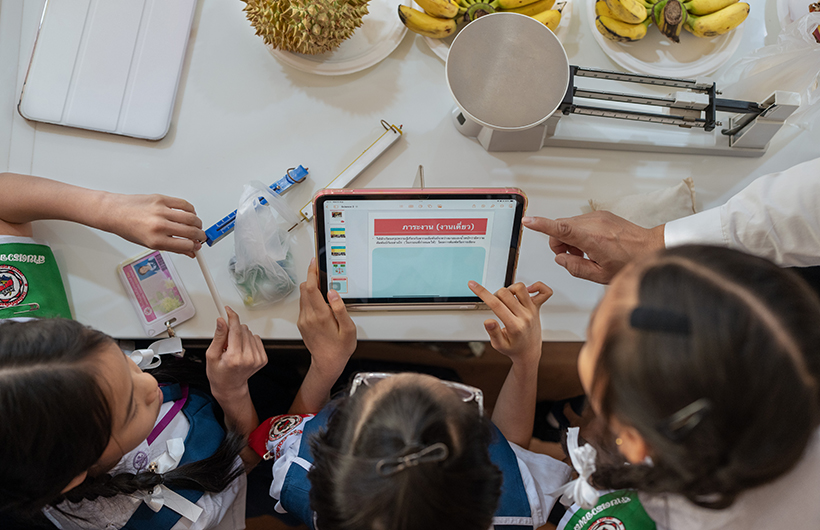 Autour d’un iPad, trois élèves du primaire réalisent ensemble une présentation pour un projet de sciences.