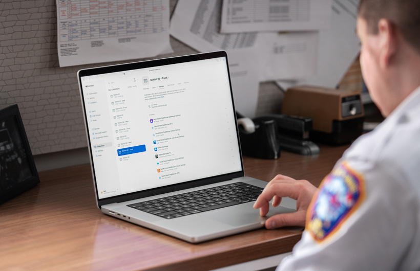 Una responsable del cuerpo de bomberos sentada en un despacho utiliza un MacBook con Apple Business Essentials abierto en la pantalla
