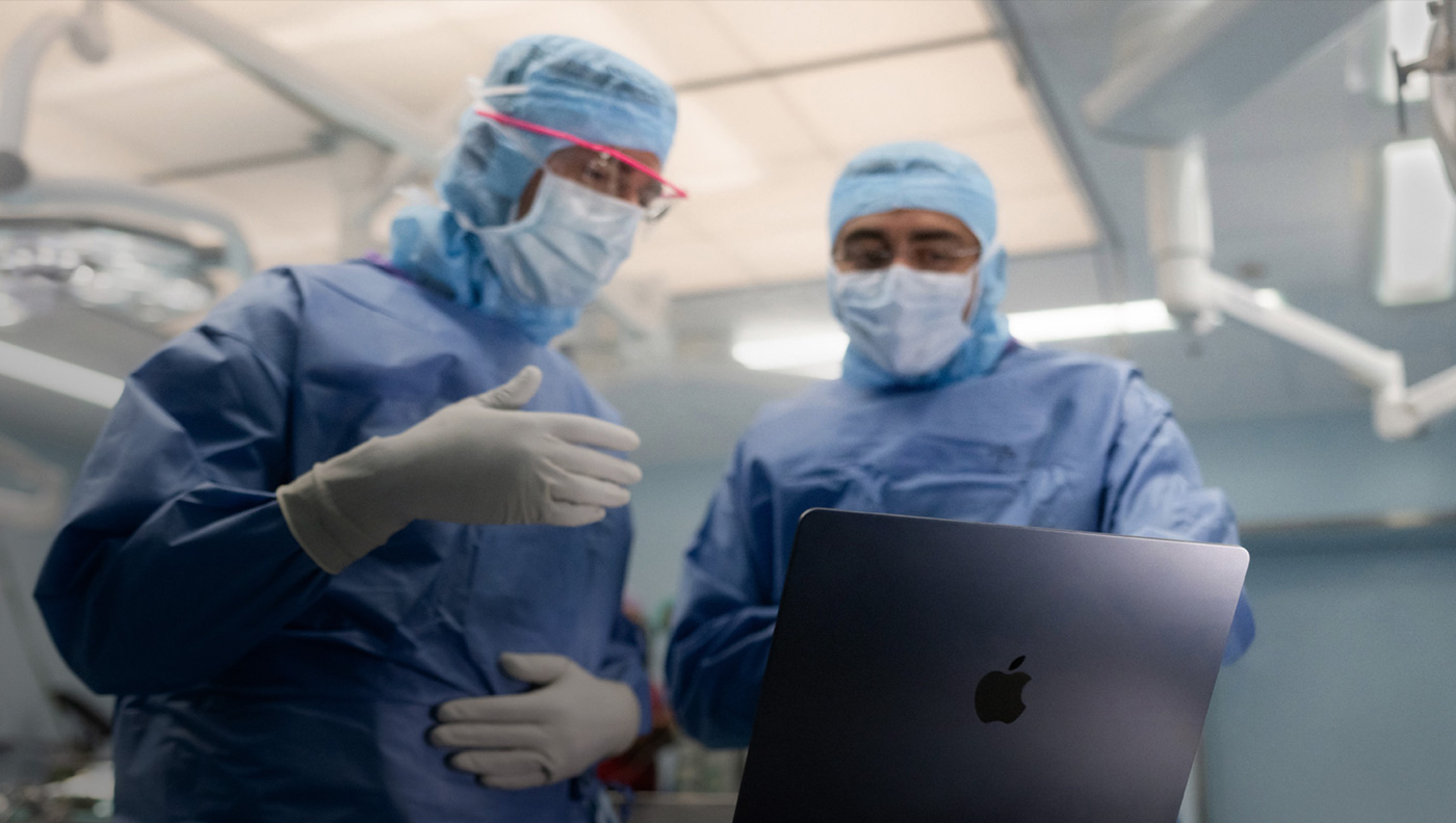 Hai bác s? ph?u thu?t ?ang th?o lu?n v? m?t n?i dung trên màn hình c?a MacBook Pro trong phòng ph?u thu?t.